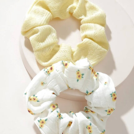 Yellow floral and ribbed scrunchy placed in a flat lay with self-care and hair accessories