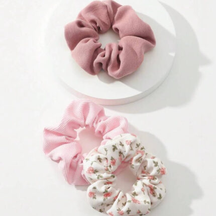 Pack of floral and rib knit scrunchies displayed on a wooden surface with delicate flowers