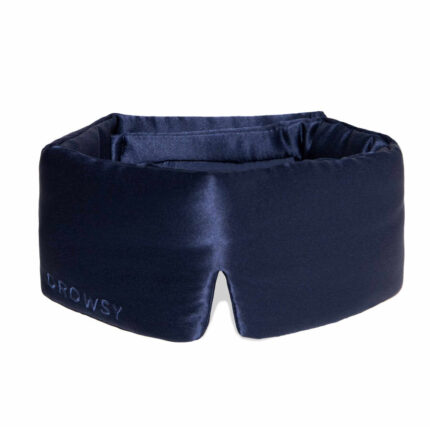 Drowsy eye mask in midnight blue silk resting on a soft gift box arrangement