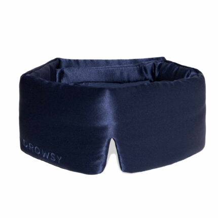 Drowsy eye mask in midnight blue silk resting on a soft gift box arrangement