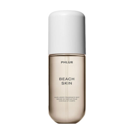 Phlur Beach Skin Hair and Body Mist bottle styled with summer-themed beauty items in a gift box