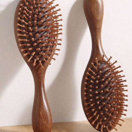 Two natural wooden hair brushes standing on a wooden surface