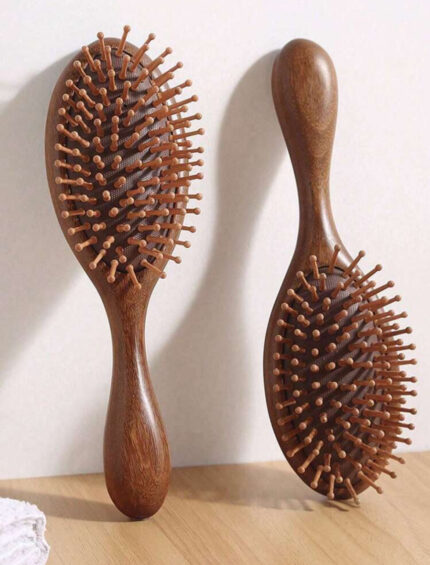 Two natural wooden hair brushes standing on a wooden surface