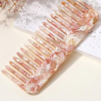 Pink marble comb with floral detailing, curved shape, and wide teeth – perfect for gentle detangling