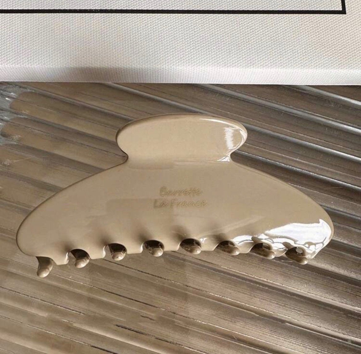 Screenshot Glossy beige claw clip hair accessory on textured surface
